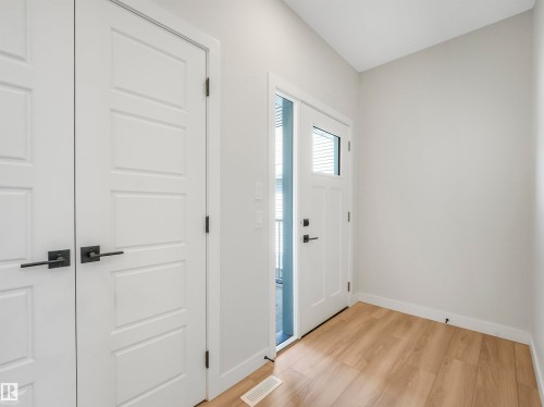 Wood-finish flooring, white paneled doors, matte black hardware, and an entry door with an integrated glass panel - 11 Dalquist Bay, Leduc, AB 