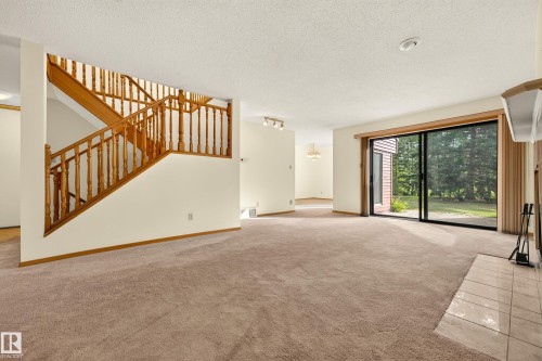 Spacious living area with plush carpeting and a tile-surround fireplace - #23 500 Lessard Dr Nw, Edmonton, AB 