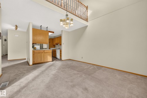 Vaulted ceiling, open-concept design, wood cabinetry, built-in kitchen appliances, and a second-story interior balcony with wood balusters - #23 500 Lessard Dr Nw, Edmonton, AB 