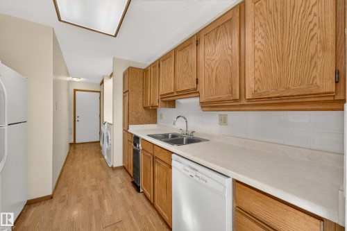 Wood-finish flooring throughout, full-size washer and dryer, and white tile backsplash - #23 500 Lessard Dr Nw, Edmonton, AB 