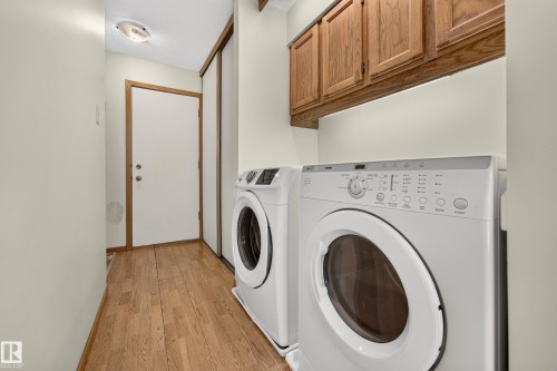 Utility area featuring wood-finish flooring, built-in upper cabinetry, and a flush-mount ceiling light fixture - #23 500 Lessard Dr Nw, Edmonton, AB 