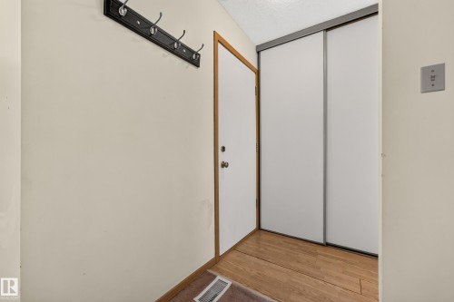 Wood-finish flooring, white walls, and a black coat rack with chrome hooks - #23 500 Lessard Dr Nw, Edmonton, AB 