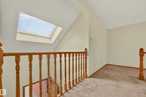 Loft area with a skylight, carpet flooring, and wood-finish railings - #23 500 Lessard Dr Nw, Edmonton, AB 