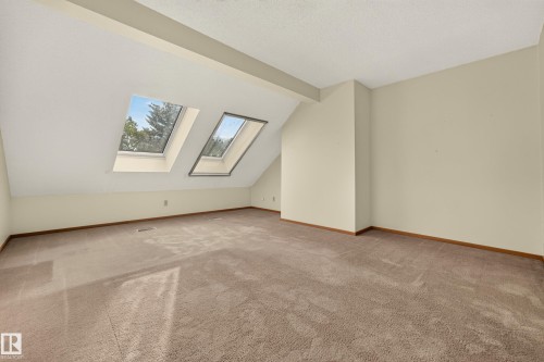 Sloped ceiling with two skylights, recessed lighting, neutral wall paint, and carpet flooring - #23 500 Lessard Dr Nw, Edmonton, AB 
