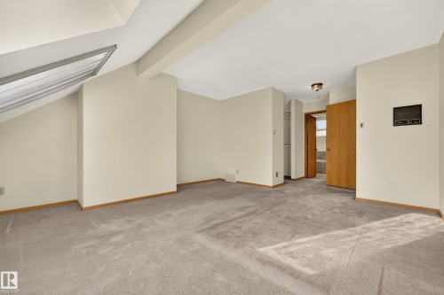 Angled ceiling with skylight, neutral wall paint, light-colored carpeting, wood-finish trim, and recessed closet space - #23 500 Lessard Dr Nw, Edmonton, AB 