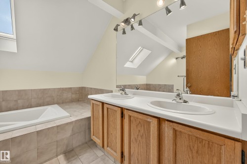 Dual vanity with integrated sinks, wood cabinetry, large mirror, and track lighting - #23 500 Lessard Dr Nw, Edmonton, AB 