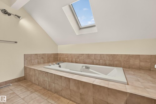 Built-in soaking tub with tile surround, skylight, sloped ceiling, and tiled flooring - #23 500 Lessard Dr Nw, Edmonton, AB 