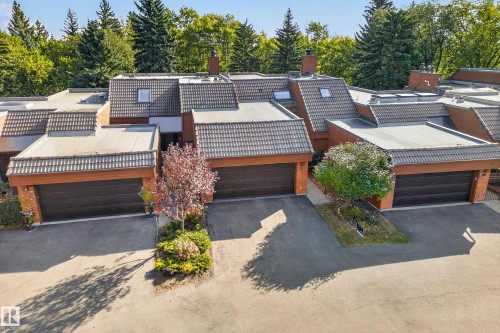 Terraced residential structures featuring multiple attached garages, peaked tile roofing, and flat roof sections - #23 500 Lessard Dr Nw, Edmonton, AB 