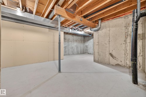 Unfinished basement featuring exposed wood joists, concrete walls, and a concrete floor - #23 500 Lessard Dr Nw, Edmonton, AB 