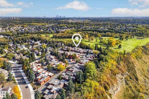 Aerial perspective showcasing a residential area with varied housing, lush trees, a golf course, and a distant city skyline - #23 500 Lessard Dr Nw, Edmonton, AB 