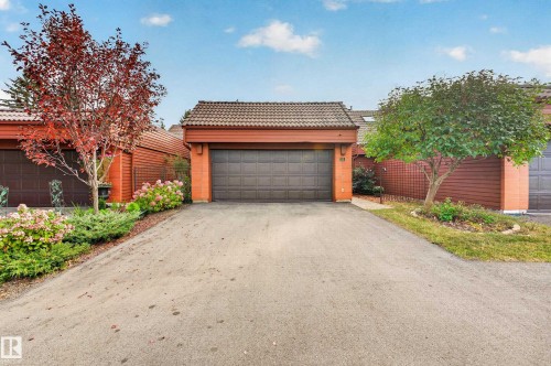 Attached garage with a panel door, brick facade, and tile roof - #23 500 Lessard Dr Nw, Edmonton, AB 