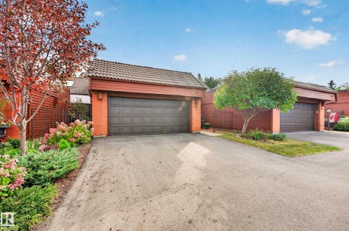 Attached garages with paneled doors, brick accents, and tile roofing - #23 500 Lessard Dr Nw, Edmonton, AB 