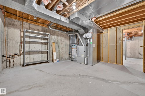 Unfinished lower level with exposed concrete walls, concrete flooring, exposed ceiling joists, and HVAC system - #23 500 Lessard Dr Nw, Edmonton, AB 