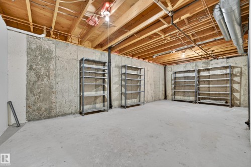 Unfinished basement featuring exposed wood joists, concrete walls, and concrete flooring - #23 500 Lessard Dr Nw, Edmonton, AB 