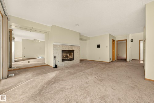 Living area with a stone-clad fireplace and neutral carpeting - #23 500 Lessard Dr Nw, Edmonton, AB 