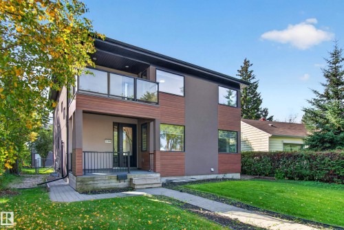 Modern architectural design featuring a second-story balcony with glass railing, a covered entryway, and a combination of wood-look siding and smooth panels - 11167 62 Avenue Nw, Edmonton, AB 
