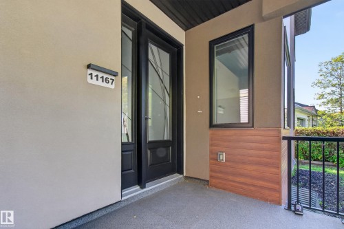 Stucco exterior with wood-finish accent paneling, a black-framed window, and a black railing - 11167 62 Avenue Nw, Edmonton, AB 