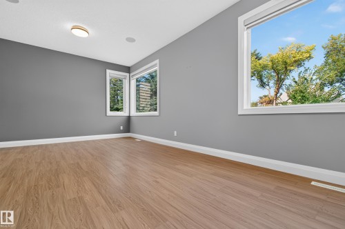 Room featuring wood-finish flooring, multiple windows, and a flush mount ceiling light - 11167 62 Avenue Nw, Edmonton, AB 