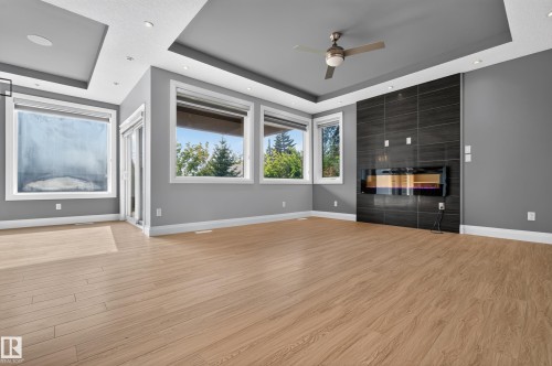 Recessed lighting with layered ceiling details, wood-finish flooring, multiple windows, built-in linear fireplace, and a ceiling fan - 11167 62 Avenue Nw, Edmonton, AB 