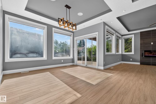 Wood-finish flooring, recessed lighting, contemporary chandelier, gas fireplace, and sliding glass doors to exterior - 11167 62 Avenue Nw, Edmonton, AB 