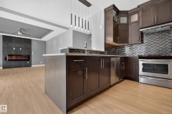 Kitchen with dark wood cabinetry, stainless steel appliances, and a tiled backsplash - 