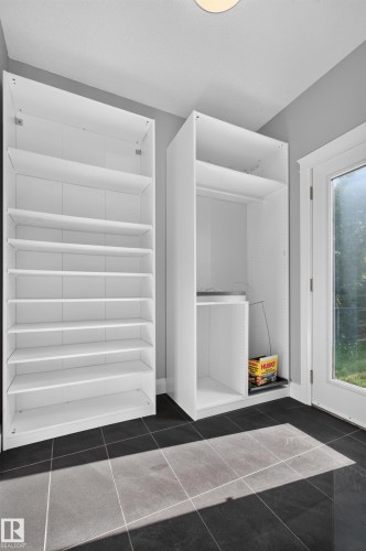 Built-in white storage cabinetry and shelving, dark tile flooring, and a glass-paneled door - 11167 62 Avenue Nw, Edmonton, AB 