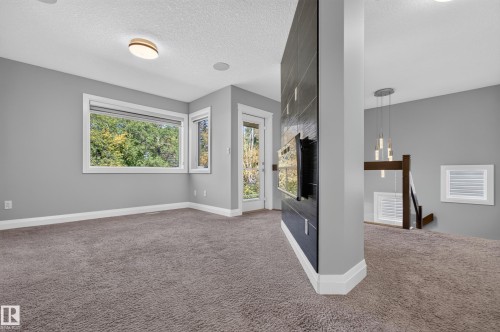 Wall-mounted oven set into a dark-tiled feature wall, complemented by a contemporary chandelier and recessed ceiling lighting - 11167 62 Avenue Nw, Edmonton, AB 