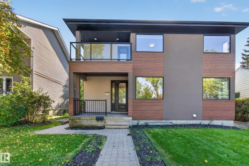 Modern facade featuring wood-finish siding, stucco accents, a flat roofline, and a second-story balcony with a glass railing - 11167 62 Avenue Nw, Edmonton, AB 