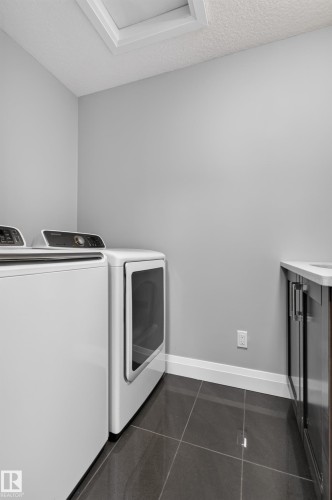 Dark-toned square floor tiling, white baseboards, light gray wall paint, and a built-in countertop with dark cabinetry - 11167 62 Avenue Nw, Edmonton, AB 