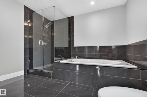 Glass-enclosed shower with a rainfall showerhead, and a built-in tub with tile surround - 11167 62 Avenue Nw, Edmonton, AB 