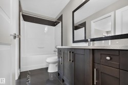 Dark-finish vanity with ample storage and a light-toned countertop, complemented by a decorative framed mirror - 