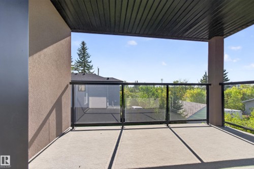 Spacious balcony with concrete flooring, glass panel railing, and a black soffit ceiling - 11167 62 Avenue Nw, Edmonton, AB 