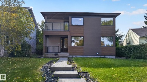 Contemporary exterior featuring wood-finish siding, dark stucco, and a second-story balcony with glass railing - 11167 62 Avenue Nw, Edmonton, AB 