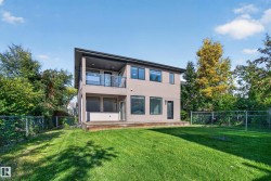 Modern two-story exterior with a neutral-toned facade, black-framed windows, and a glass-paneled balcony - 