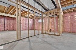 Unfinished basement with concrete flooring, exposed wood framing, and pink insulation - 