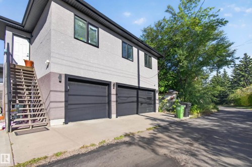Stucco exterior with black trim windows, dual garage bays, and exterior staircase entry - 11167 62 Avenue Nw, Edmonton, AB 