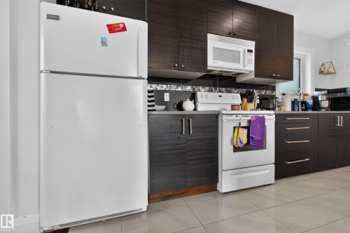 Kitchen featuring dark wood-finish cabinetry, tile flooring, and a glass tile backsplash - 11167 62 Avenue Nw, Edmonton, AB 