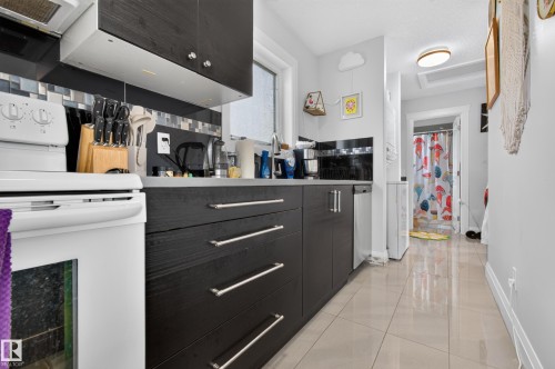White range with overhead ventilation, dark wood-finish cabinetry, and a tile backsplash - 11167 62 Avenue Nw, Edmonton, AB 