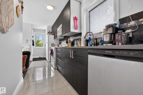Contemporary kitchen featuring dark wood-finish cabinetry, stainless steel appliances, and a tile backsplash - 11167 62 Avenue Nw, Edmonton, AB 