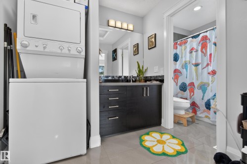 Stackable washer and dryer, vanity with dark wood-finish cabinetry, integrated sink, and wall-mounted light fixture - 11167 62 Avenue Nw, Edmonton, AB 