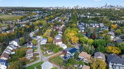 Residential neighborhood with mature trees, established streets, and a distant city skyline - 