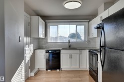 Well-appointed kitchen featuring white cabinetry, subway tile backsplash, dark countertops, and wood-finish flooring - 