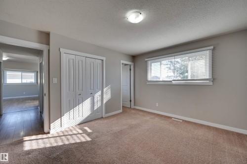 Neutral wall color, wall-to-wall carpeting, window with horizontal blinds, flush mount ceiling light, and bi-fold closet doors - 13815 88 Street Nw, Edmonton, AB 