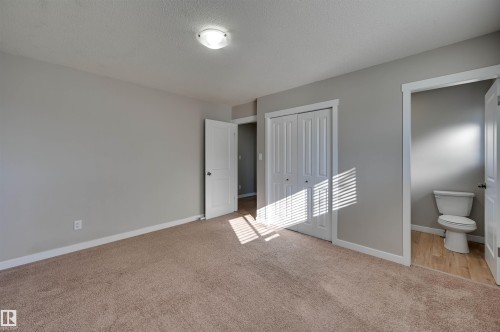 Plush carpeted flooring, neutral wall tones, white bi-fold closet doors, white interior doors, and a flush mount ceiling light fixture - 13815 88 Street Nw, Edmonton, AB 