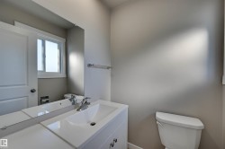 White vanity with an integrated sink, chrome faucet, and expansive mirror - 