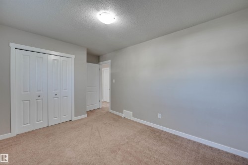 Plush carpet flooring, neutral paint palette, white bi-fold closet doors, white trim, and a flush mount ceiling light - 13815 88 Street Nw, Edmonton, AB 