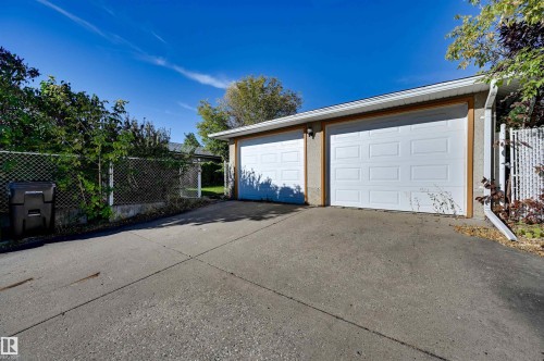 Two-car attached garage with white panel doors, wood-finish trim, and a concrete driveway - 13815 88 Street Nw, Edmonton, AB 