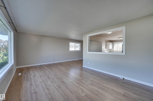 Wood-finish flooring throughout, multiple windows, and a pass-through opening to an adjacent room - 13815 88 Street Nw, Edmonton, AB 