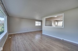 Wood-finish flooring throughout, multiple windows, and a pass-through opening to an adjacent room - 