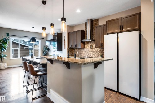 Kitchen featuring wood-finish flooring, granite countertops, and a tile backsplash - 337 Southfork Drive, Leduc, AB 